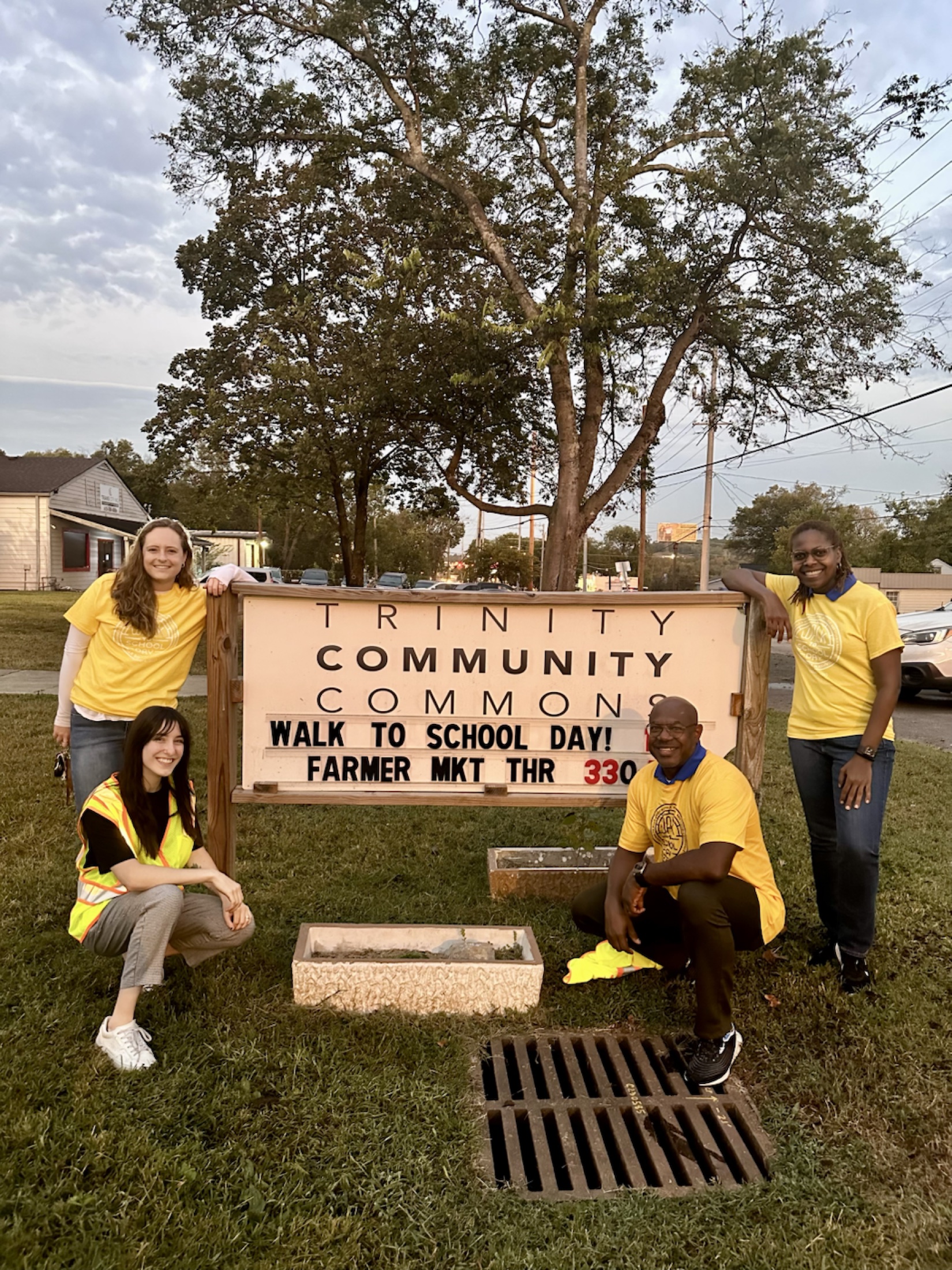 Fairpointe and partner staff gather beside a Walk to School Day sign at Trinity Community Commons.