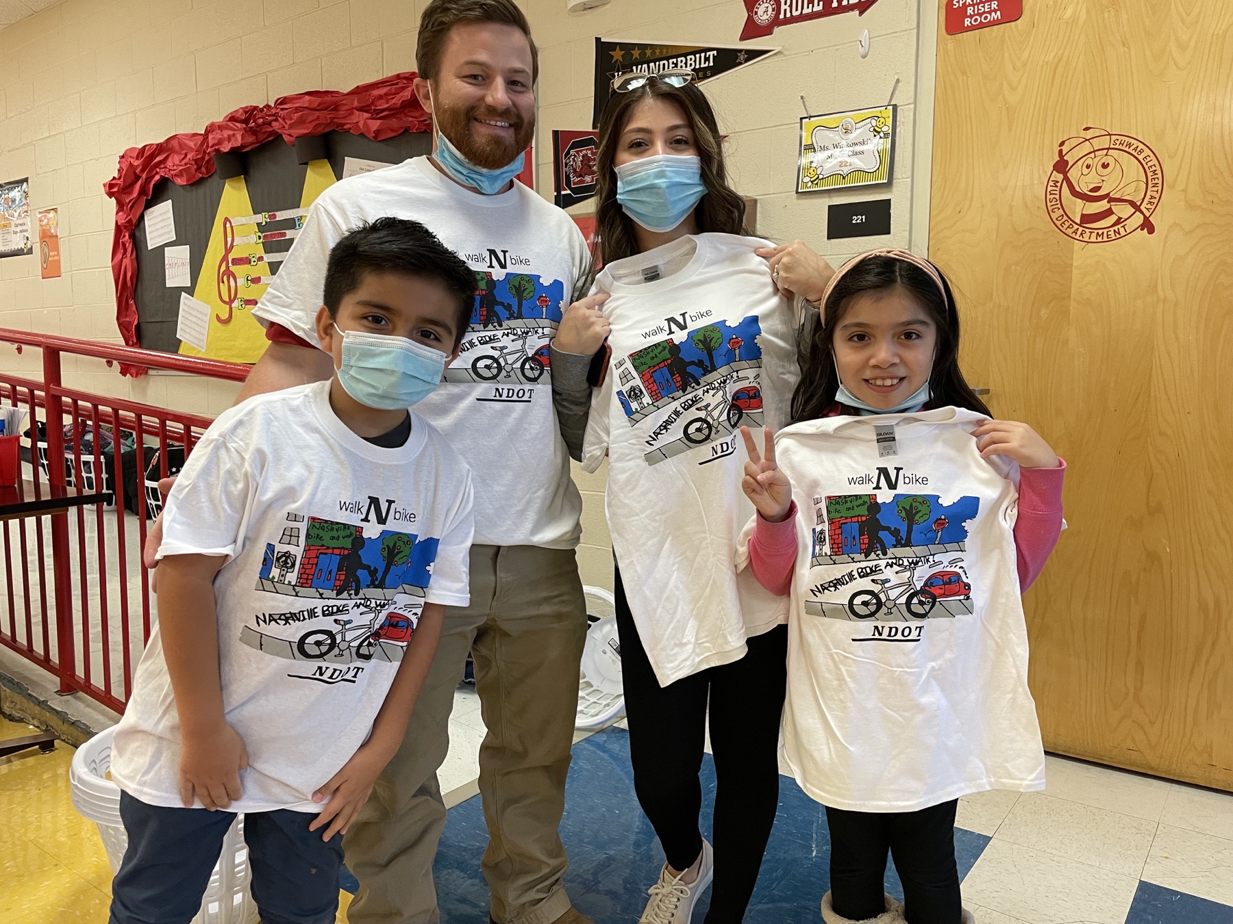 Students and project partners hold Nashville WalknBike artwork shirts during school outreach.