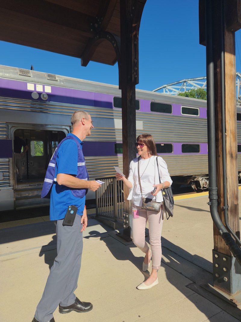 A project team member speaks with a passenger beside a WeGo Star train at Riverfront Station.